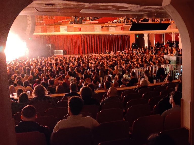 Trusted Network of Specialist Partners A large audience seated in a theatre, facing a bright stage.