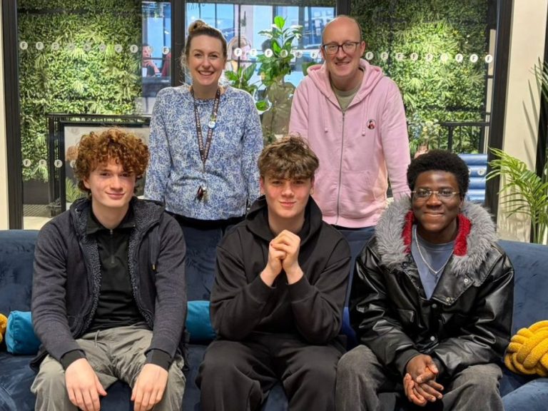 Local Content Producers Brian, a business client, and 3 content creators smiling together, seated on a sofa in a casual office space.