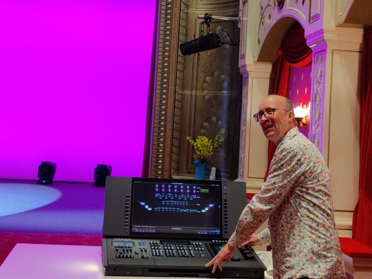 Technical Support Brian demonstrates a stage lighting console with a colourful backdrop.